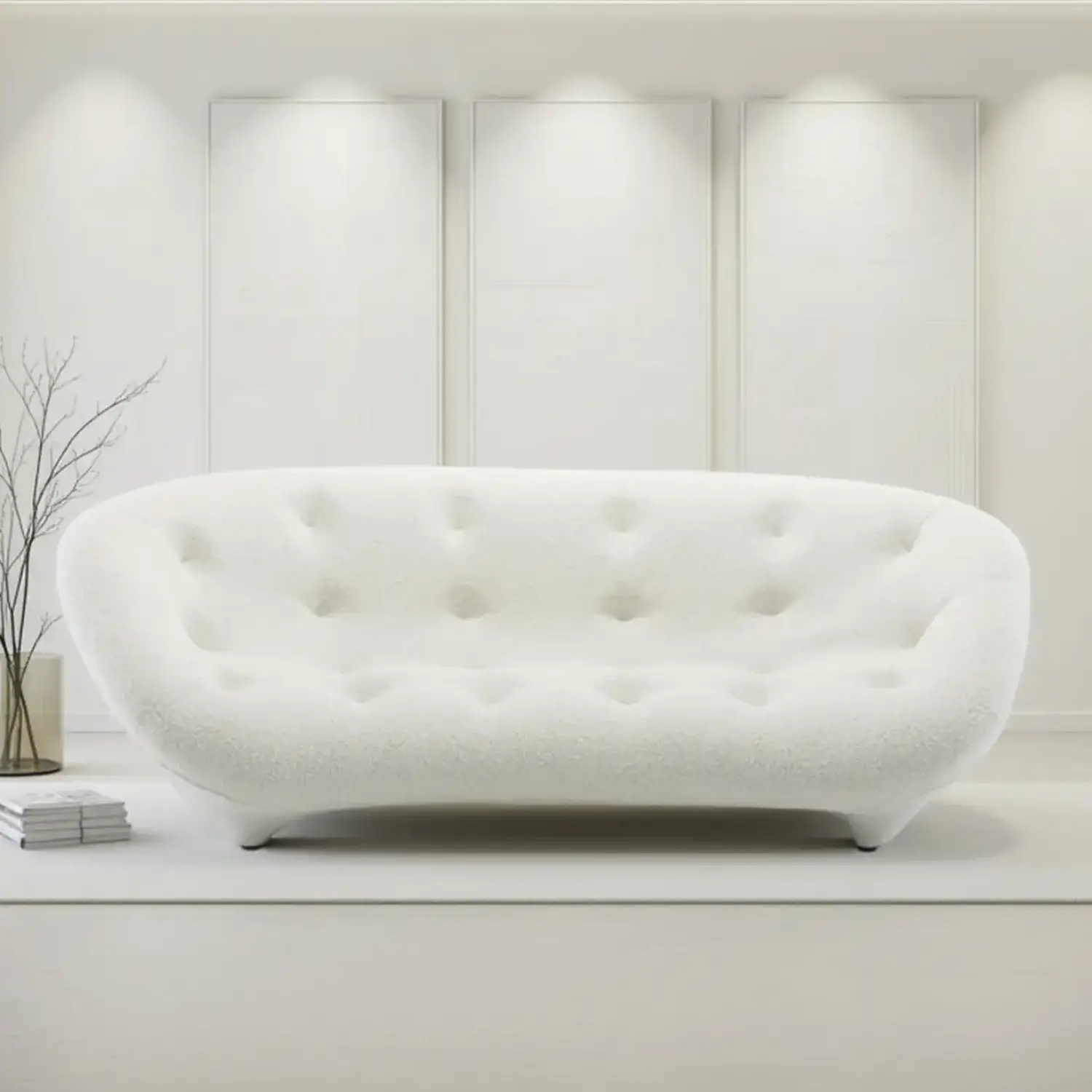 Curved modern white tufted sofa in a minimalist room with light walls and a small vase with branches next to it.