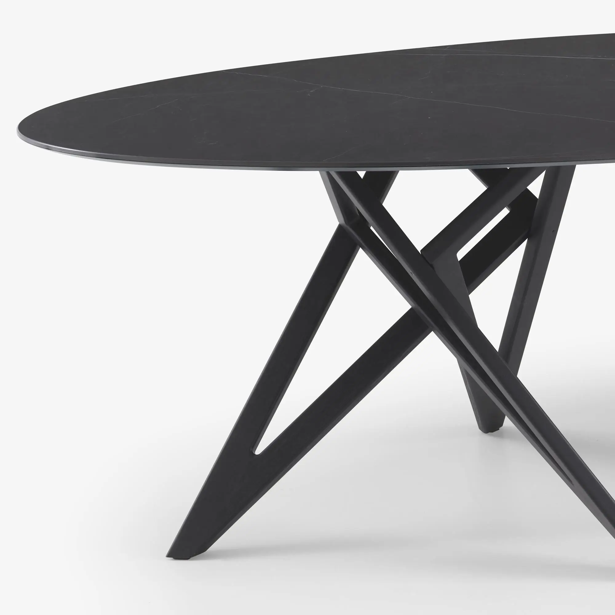 Close-up of a modern black table with a smooth round top and angular intersecting legs.